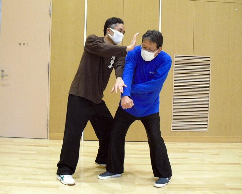 楊式太極拳 摟膝拗歩の用法例の写真2
相手の両腕を交差して封じたまま、相手の頭部を掌で打っている写真